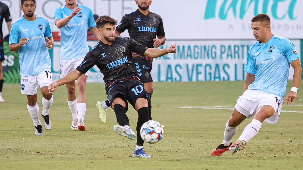 Las Vegas Lights midfielder Edison Azcona kicking a ball past a Colorado Springs Switchbacks player